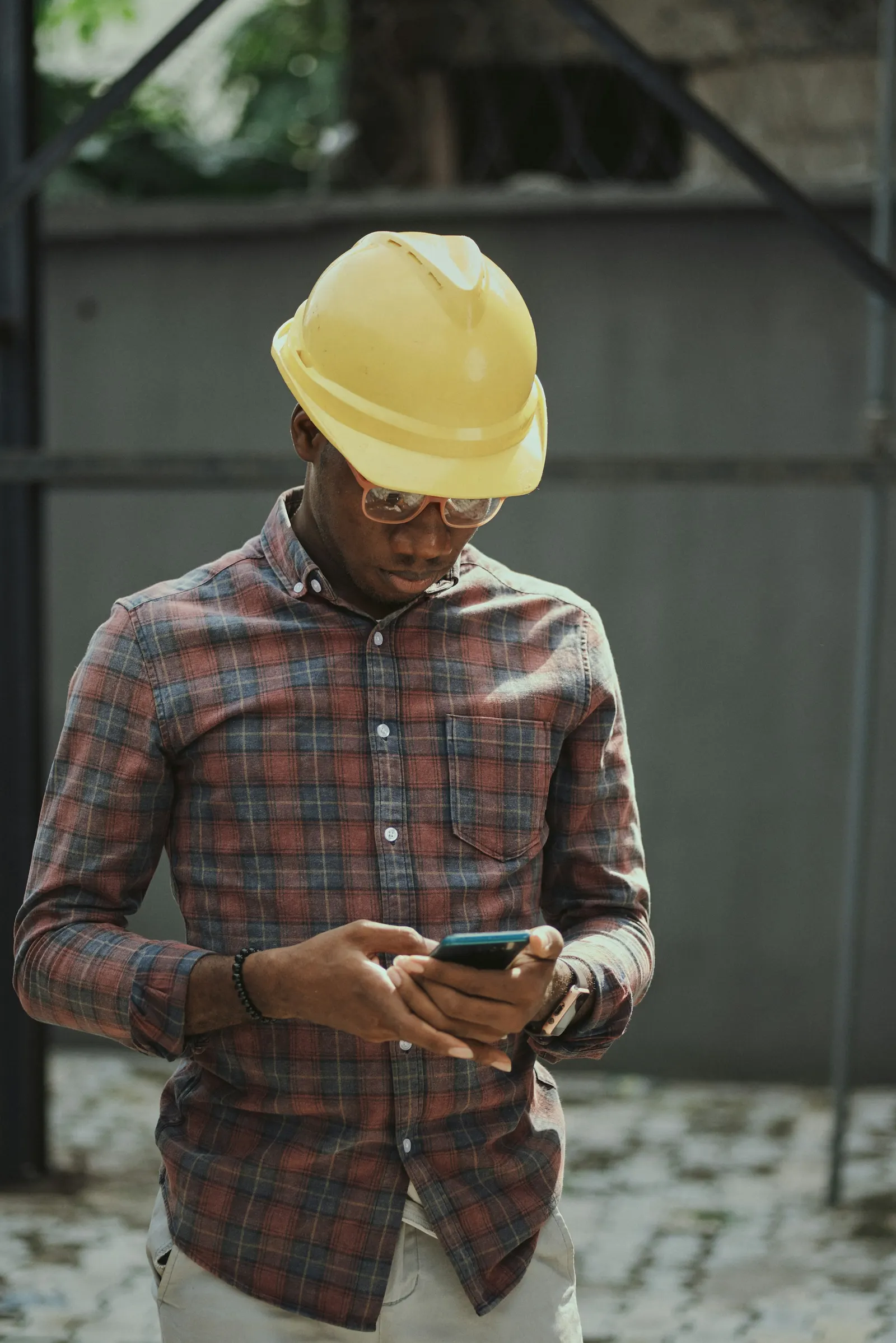 Field technician in a yellow hard hat checking a job on his phone